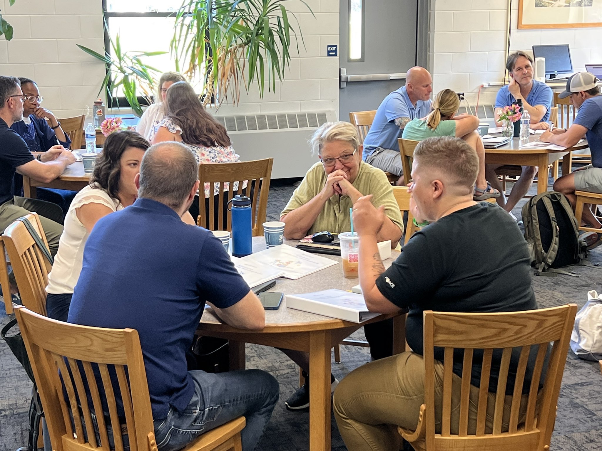 Group of teachers sitting together at a round table discussing a topic.